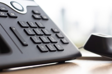 Close up IP phone for office on the table desk with window city view .