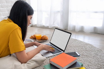 Poster - Asian female freelancer working on laptop computer at home.woman lying down on carpet at brick wall.working online lifestyle.mock up screen with clipping path.