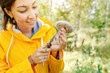 A woman in a bright yellow jacket picking mushrooms in an autumn forest. Concept of outdoor recreation