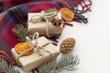 Christmas gifts in craft paper with fir branches, dried mandarin, anise and cone on the cozy plade. Copy space