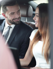 Smiling business people working in backseat of car