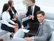© ASDF - businessman sitting in an office on the background of business team.