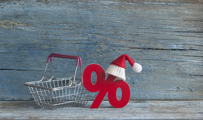 sign percent and shopping cart on wood background