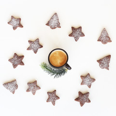 Wall Mural - Gingerbread cookies in the shape of a Christmas tree and stars with icing sugar are lined in a circle around a cup of coffee with a fir branch on a white background. Top view, flat lay