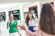 © LIGHTFIELD STUDIOS - selective focus of cheerful young women greeting each other in shopping mall