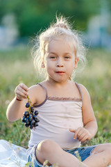 Wall Mural - cute little girl eating grapes in the park