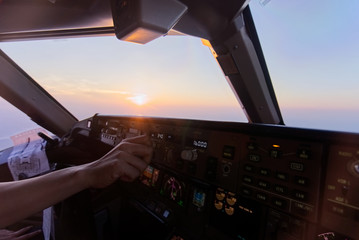 Wall Mural - In airplane cockpit view from Co pilot seat, airplane flying over the cloud during sunset in the evening. Able to see beautiful twilight outside the cockpit while pilot working in cockpit.