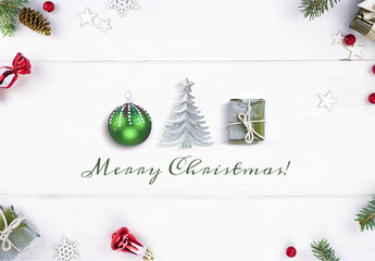 Wall Mural - Greeting Festive Christmas composition of green ball, Christmas tree and gift on white wooden boards in frame fir branches flat lay with inscription Merry Christmas!