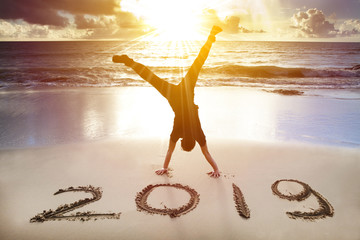 young man handstand on the beach.happy new year 2019 concept