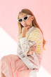 adorable fashionable youngster in trendy sunglasses posing on pink