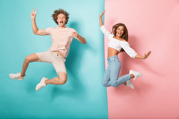 Wall Mural - Full length portrait of a joyful young couple jumping