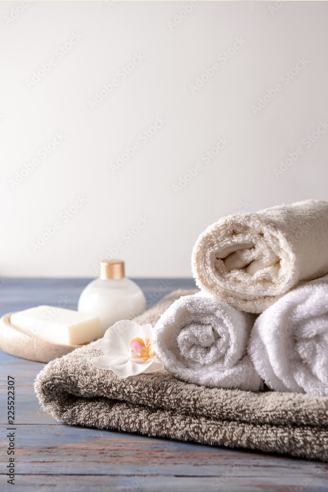 Stack of clean soft towels with flower on wooden table