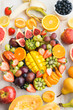 Variety of cut fruits and berries platter, strawberries blueberries, mango orange, apple, grapes, kiwis on the white wood background, copy space for text, layout, top view, selective focus