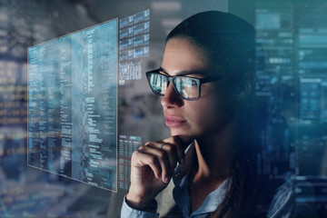 Close up of a beautiful girl with glasses while she is working with a futuristic computer with holograms. Concept: Future, technology, work