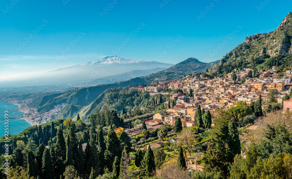 A panoramic view of Taormina, Giardini Naxos and Mount Etna, in Sicily, Italy. Photo taken from Via Teatro Greco, in Taormina. - obrazy, fototapety, plakaty 
