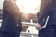 © khwanchai - Successful negotiating business concept, Businessmen shaking hands after finishing meeting or setting  goals and planning way to success in front of building
