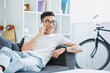 © LIGHTFIELD STUDIOS - smiling handsome asian man lying on sofa and talking by smartphone at home