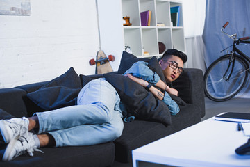 Wall Mural - young asian man in eyeglasses sleeping on sofa at home