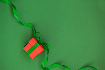 one red christmas gift box with green ribbon on green background