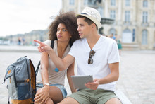 Young Couple Of Tourists Looking At Tablet Screen Outdoors