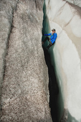 A free climber without insurance with two ice axes rises from a crack in the glacier. Free climbing without ropes