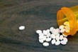 Pile of white pills spilled from a prescription bottle. Concepts of opioid addiction, prescription drug abuse and crisis