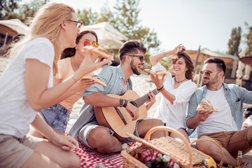 Canvas Print - Group of happy young people having picnic on the beach