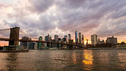 Sticker - New York, USA. View of Manhattan bridge and Manhattan in New York, USA at sunset. Colorful cloudy sky with skyscrapers. Sun setting behind the skyscrapers. Time-lapse at sunset