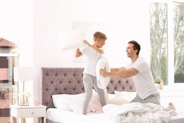 Canvas Print - Father and son having pillow fight on bed at home