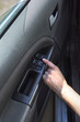 Kobieca dłoń dotyka przycisk regulacji szyb w samochodzie.