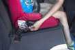 Dziecko w samochodzie w foteliku. Kobieta zapina i zakłada pas bezpieczeństwa.