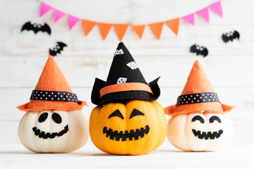 Wall Mural - White and yellow ghost pumpkins with witch hat on white wooden borad background with bat. halloween concept.