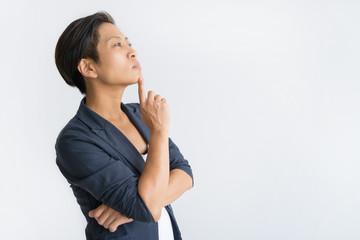 Wall Mural - Thoughtful Asian business woman touching chin with finger. Young lady looking away. Contemplation concept. Isolated side view on white background.