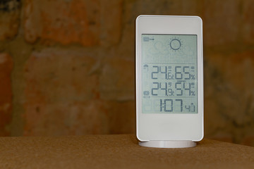 Wall Mural - Home weather station device with weather conditions inside and outside on a brick background.