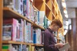 © Wavebreak Media - College student reading a book in library