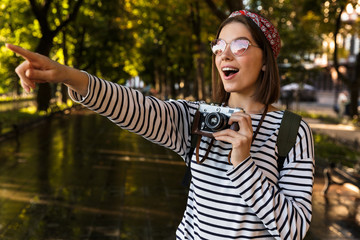 Sticker - Excited young beautiful woman walking outdoors with camera.