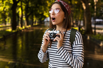 Sticker - Excited young beautiful woman walking outdoors with camera.