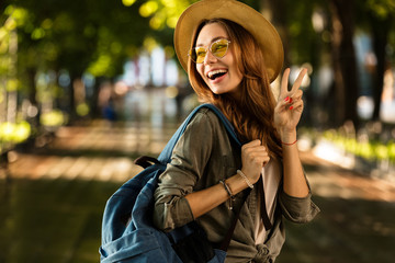 Sticker - Excited beautiful young happy woman walking outdoors with backpack.