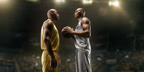 Two black basketball players on big professional arena before the game. Two teams. Players collided face to face. Player holds a ball