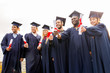 © Syda Productions - education, graduation and people concept - group of happy international students in mortar boards and bachelor gowns with diplomas
