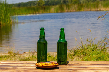 Two bottles of beer on wooden table near a river