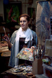 Fototapeta Paryż - Young woman artist painting with oil paints in the studio workshop