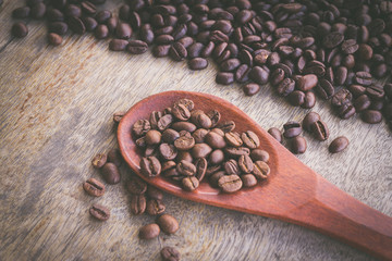 Coffee Beans in wooden spoon on old wood background with vintage filter