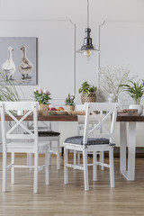 Wall Mural - White chairs at wooden table in cottage dining room interior with flowers and poster. Real photo