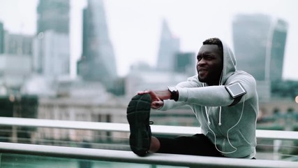 Poster - Black man runner with smartphone in an armband on the bridge in a city, stretching.