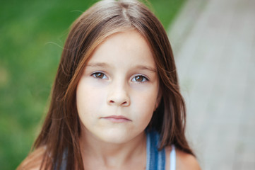 model little beautiful girl with long hair, street fashion near the wall on a summer
