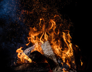 Burning wooden logs in fire, campfire on black