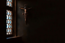The Crucifix, A Cross With Jesus Hanging On The Wall, Rays Of Light Gently Illuminate It