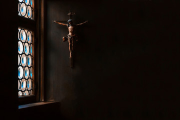 the crucifix, a cross with jesus hanging on the wall, rays of light gently illuminate it