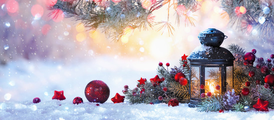 christmas lantern on snow with fir branch in the sunlight. winter decoration background